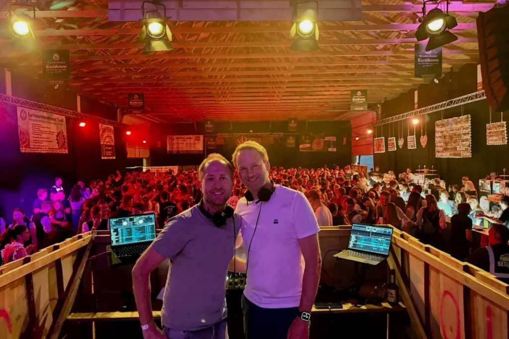 Zwei DJs von Herzschlag Events vor dem vollen Festzelt eines Vereinsfests