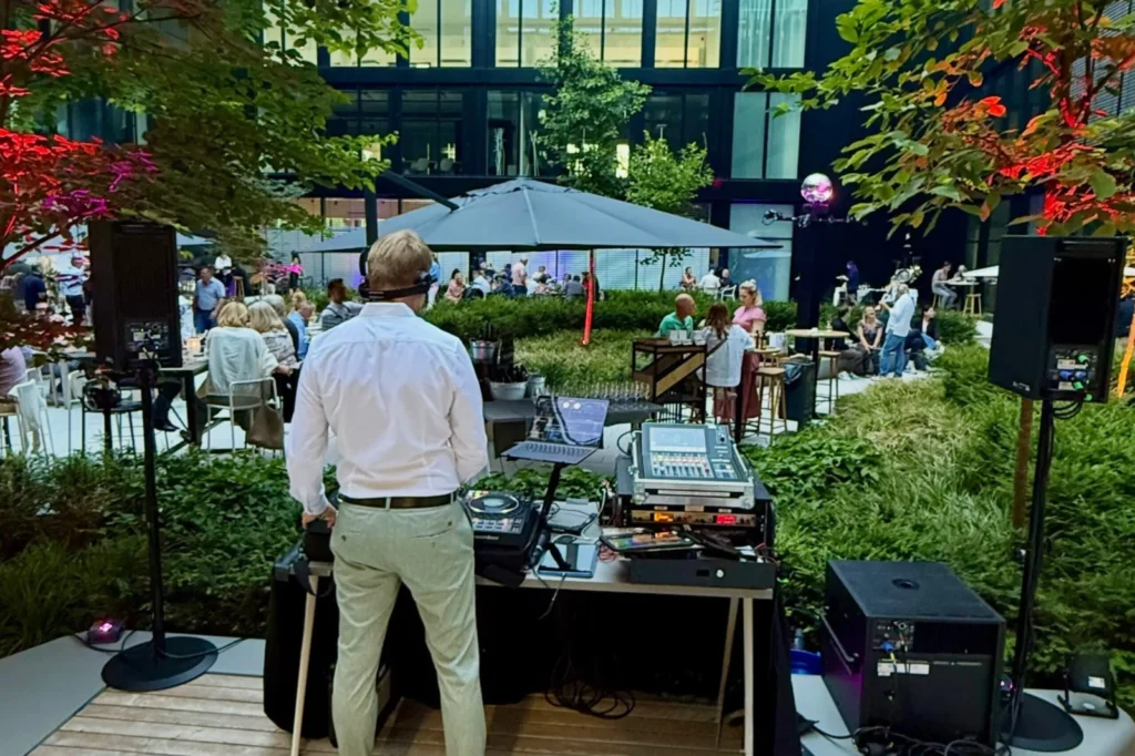 DJ am Pult bei einem Firmen-Sommerfest im Innenhof eines Bürogebäudes